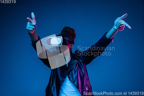Image of Young african-american woman\'s using VR-glasses in neon light