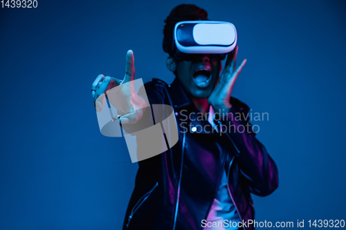 Image of Young african-american woman\'s using VR-glasses in neon light