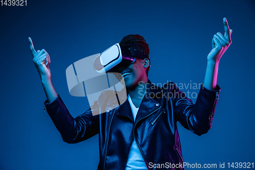 Image of Young african-american woman\'s using VR-glasses in neon light