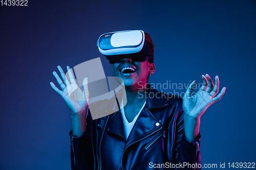 Image of Young african-american woman\'s using VR-glasses in neon light
