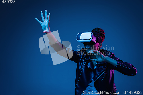 Image of Young african-american woman\'s using VR-glasses in neon light