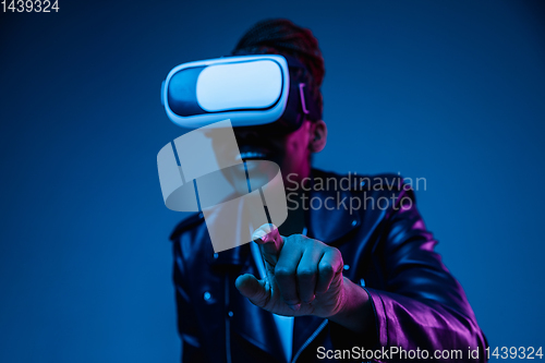 Image of Young african-american woman\'s using VR-glasses in neon light