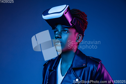 Image of Young african-american woman\'s using VR-glasses in neon light