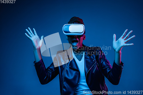 Image of Young african-american woman\'s using VR-glasses in neon light
