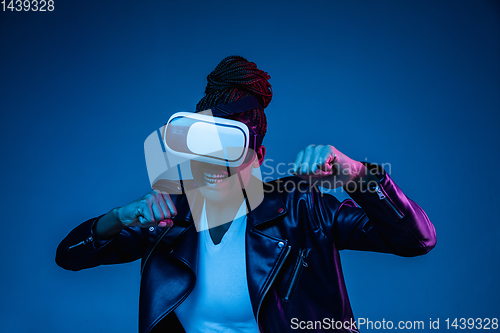 Image of Young african-american woman\'s using VR-glasses in neon light