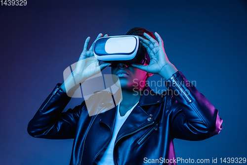 Image of Young african-american woman\'s using VR-glasses in neon light