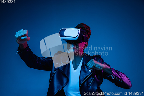 Image of Young african-american woman\'s using VR-glasses in neon light