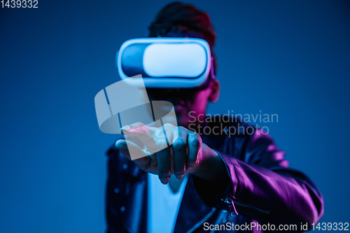 Image of Young african-american woman\'s using VR-glasses in neon light