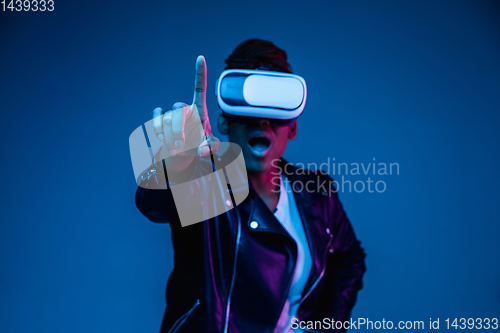 Image of Young african-american woman\'s using VR-glasses in neon light