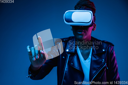 Image of Young african-american woman\'s using VR-glasses in neon light