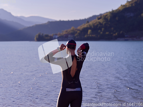 Image of authentic triathlon athlete getting ready for swimming training on lake