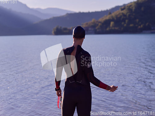 Image of authentic triathlon athlete getting ready for swimming training on lake