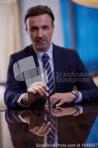 Image of corporate businessman at luxury office pen holding