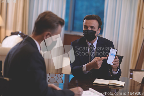 Image of business people wearing crona virus protection face mask on meeting