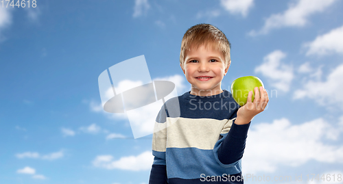 Image of smiling little boy with green apple over blue sky