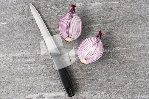 Image of cut red onion and knife on slate stone background