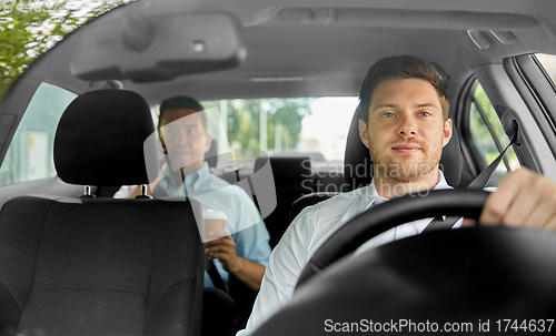 Image of male taxi driver driving car with passenger