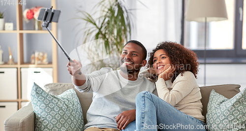 Image of couple taking picture by selfie stick at home