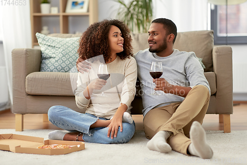 Image of happy couple with wine and takeaway pizza at home