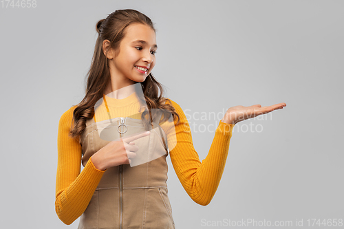 Image of happy teenage girl holding something on empty hand