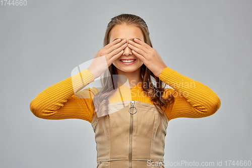 Image of smiling teenage girl closing her eyes by hands