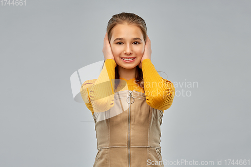 Image of smiling teenage girl closing ears by hands