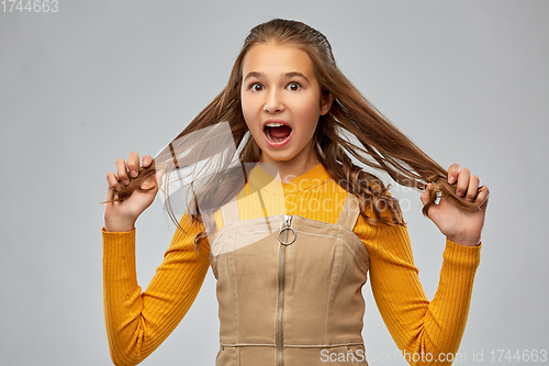 Image of scared young teenage girl holding her hair strands