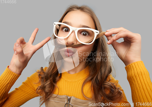 Image of teen girl in glasses makes faces and shows peace