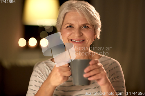 Image of happy senior woman with cup of tea at home