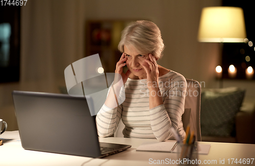 Image of tired senior woman with laptop at home at night