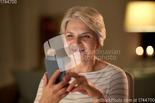 Image of happy senior woman with smartphone at home