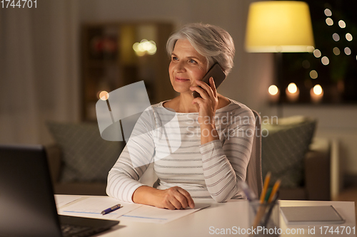 Image of old woman calling on smartphone at home at night