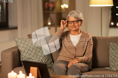 Image of happy senior woman with tablet pc at home at night