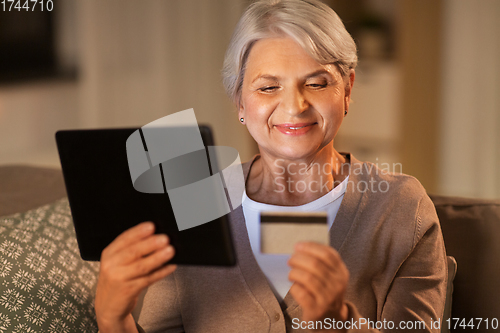 Image of old woman with tablet pc and credit card at home