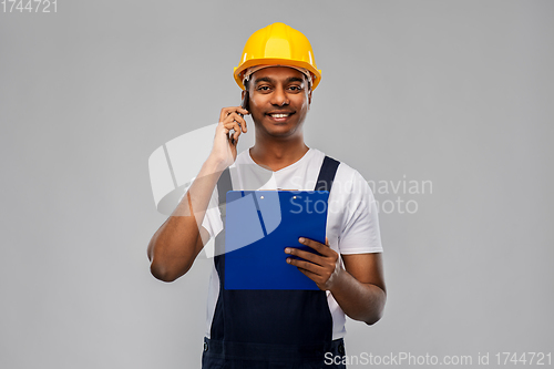 Image of indian builder with clipboard calling on cellphone
