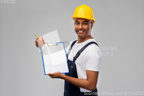 Image of happy builder in helmet with clipboard and pencil