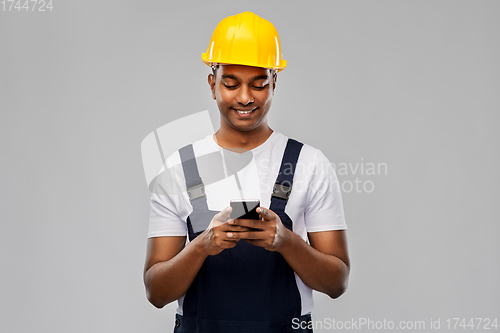 Image of happy indian or builder in helmet using smartphone