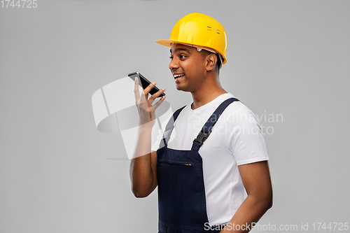 Image of happy indian builder recording voice on smartphone