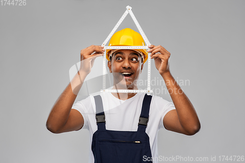 Image of happy indian builder with ruler in shape of home