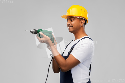 Image of happy indian builder in helmet with electric drill