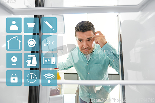 Image of man looking for food in empty fridge at kitchen