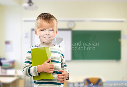 Image of portrait of smiling boy holding book at school