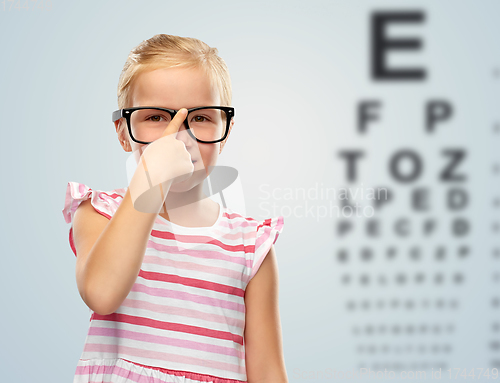 Image of smiling little girl in glasses over eye test chart