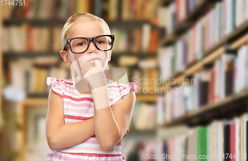 Image of little girl in black glasses thinking at library