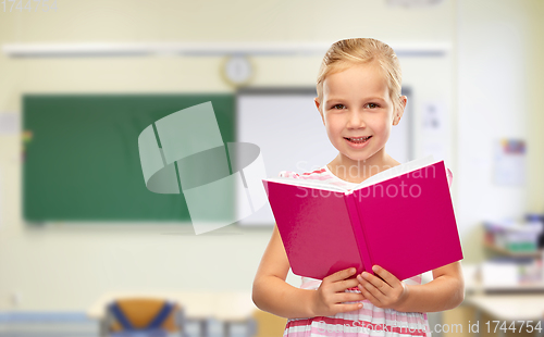 Image of smiling little girl reading book at school