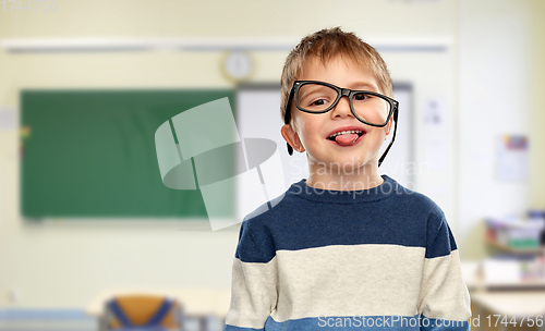 Image of little boy in glasses showing tongue at school