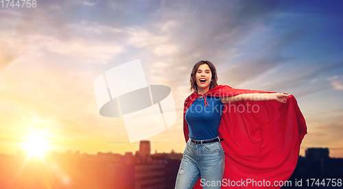 Image of happy woman in red superhero cape over city sunset