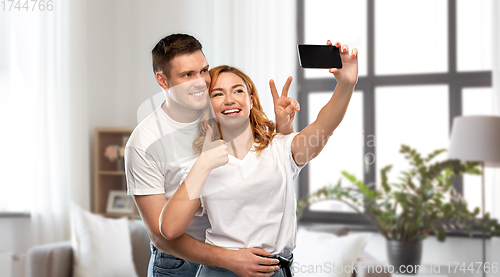 Image of happy couple in white t-shirts taking selfie