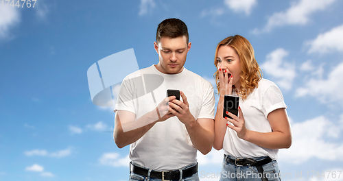 Image of happy couple in white t-shirts with smartphones