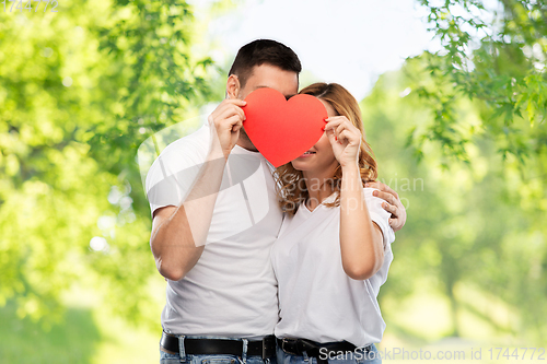 Image of smiling couple hiding behind big red heart
